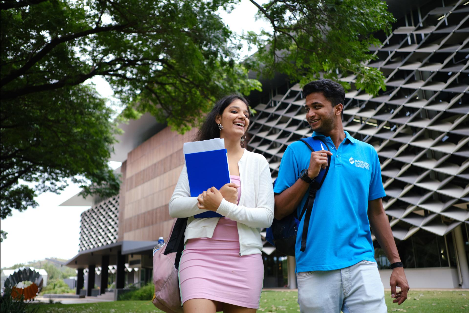 Male and female JCU students walking past The Science Place building at JCU Townsville, Queensland.